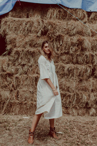 Woman in pale Kerala shirt dress standing in front of hay stack
